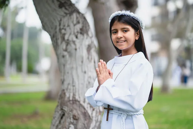 Ni&ntilde;a rezando junto a un &aacute;rbol el d&iacute;a de su primera comuni&oacute;n
